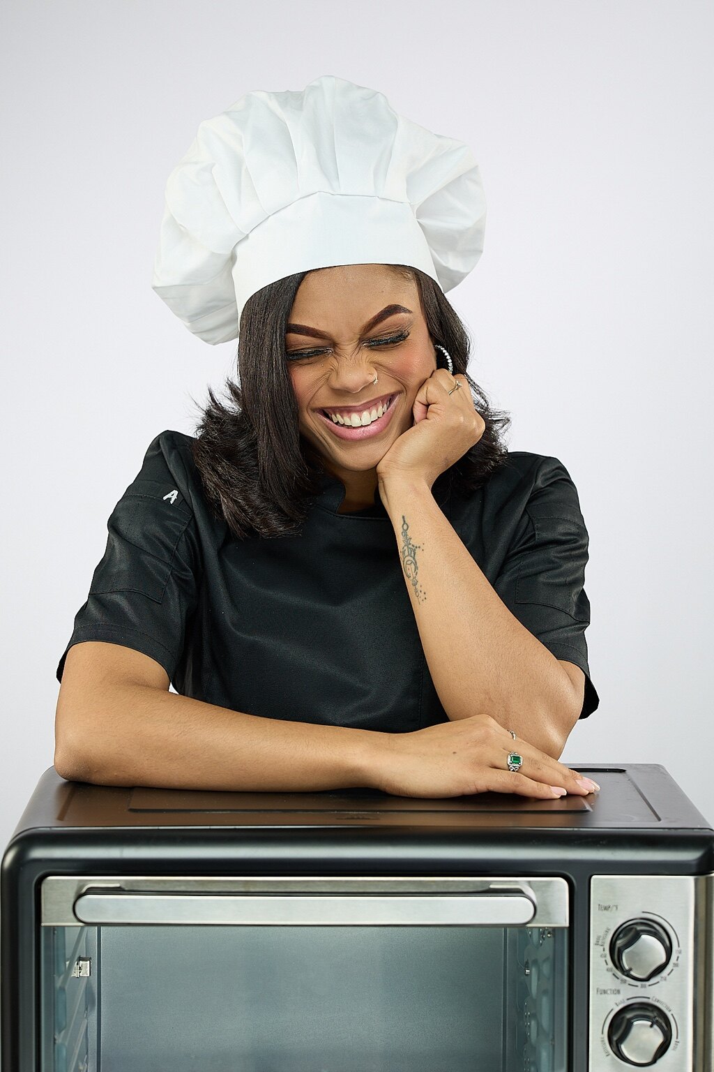 Chef Kai Smith laughing beside a countertop oven