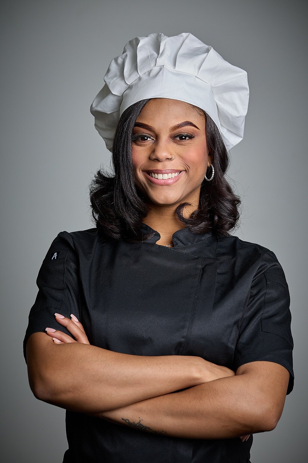 Chef Kai Smith in a black chef coat and white chef hat