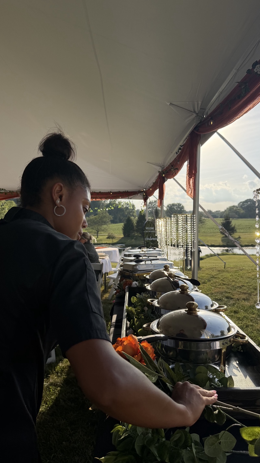 Chef Kai arranging florals along an outdoor wedding buffet